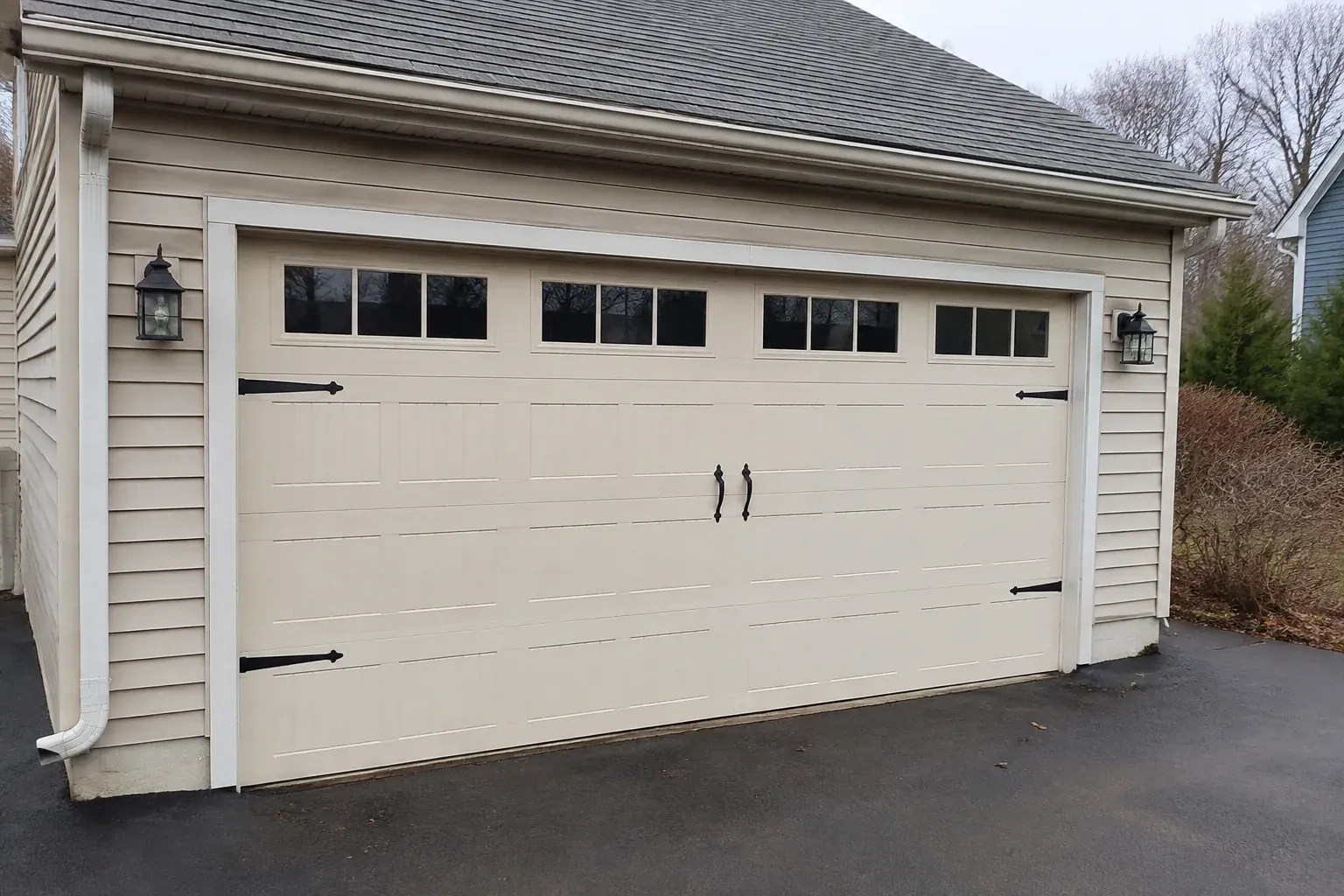 Cream carriage-house-style garage door with dark decorative hardware. — Carriage-House Garage Door Installation, Oakville